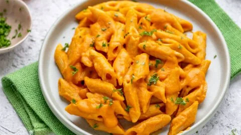 Cremige Kürbispasta auf einem Teller, dekorativ angerichtet mit frischen Kräutern.