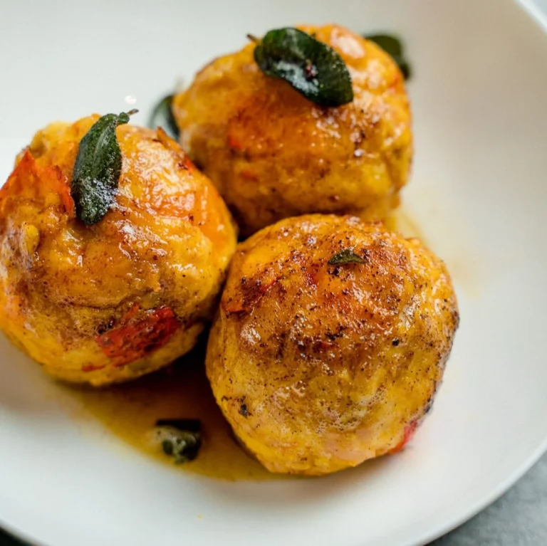 Hausgemachte Kürbisknödel mit aromatischer Salbeibutter serviert.